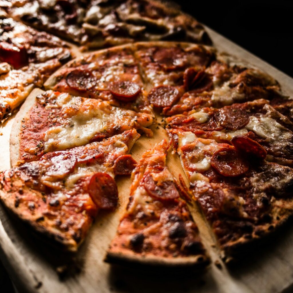 Delicious crispy pepperoni pizza slices on a wooden board, perfect for pizza lovers.